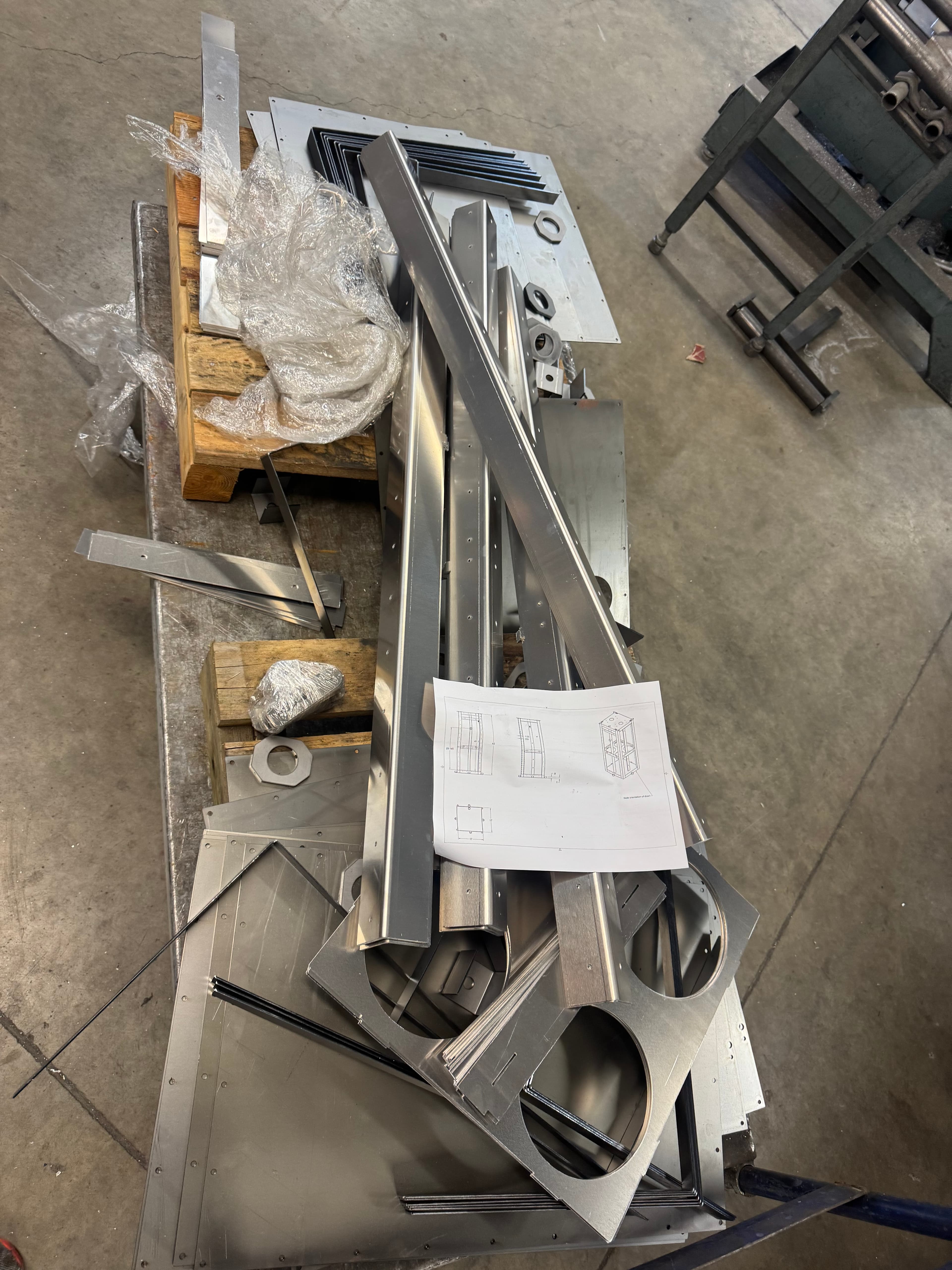 Cut stainless steel components and blueprints on the factory floor